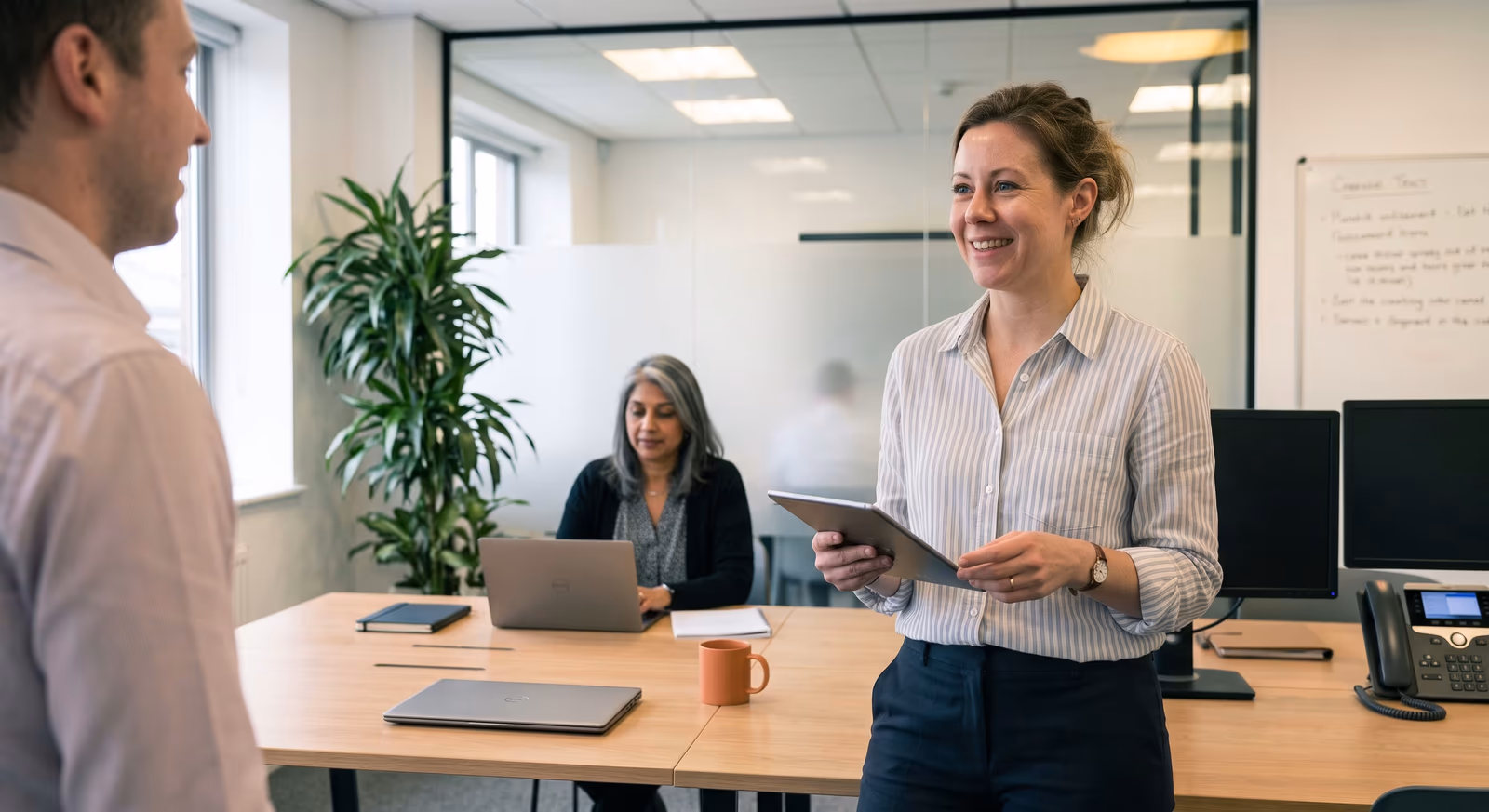 Insurance professionals discussing a portfolio in an open-plan office, one of them holding a tablet